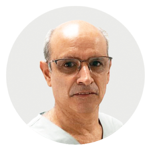 Anestesiologo Pablo, de piel clara,  ojos marrones, pelo corto y canoso, sonriente con túnica blanca